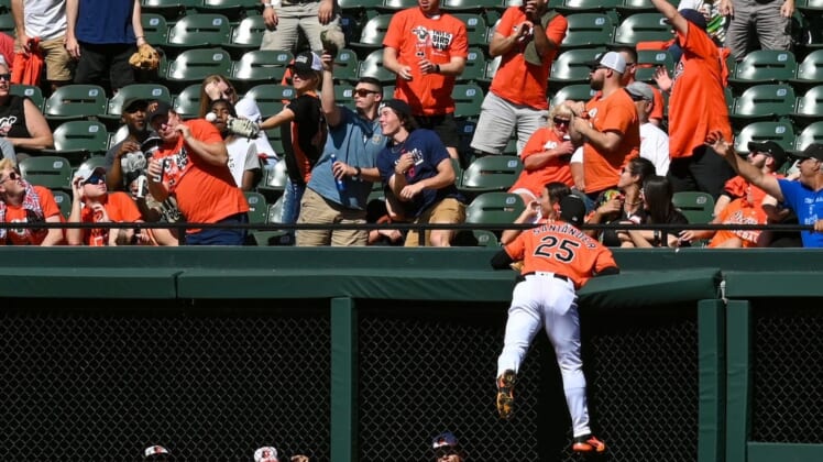 Jun 4, 2022; Baltimore, Maryland, USA; Baltimore Orioles right fielder Anthony Santander (25) climbs the outfield wall as fans attempt to catch Cleveland Guardians third baseman Jose Ramirez (not pictured) first inning solo home run  at Oriole Park at Camden Yards. Mandatory Credit: Tommy Gilligan-USA TODAY Sports