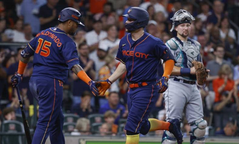 Jun 6, 2022; Houston, Texas, USA; Houston Astros center fielder Chas McCormick (20) celebrates with catcher Martin Maldonado (15) as Seattle Mariners catcher Cal Raleigh (29) looks on during the second inning at Minute Maid Park. Mandatory Credit: Troy Taormina-USA TODAY Sports