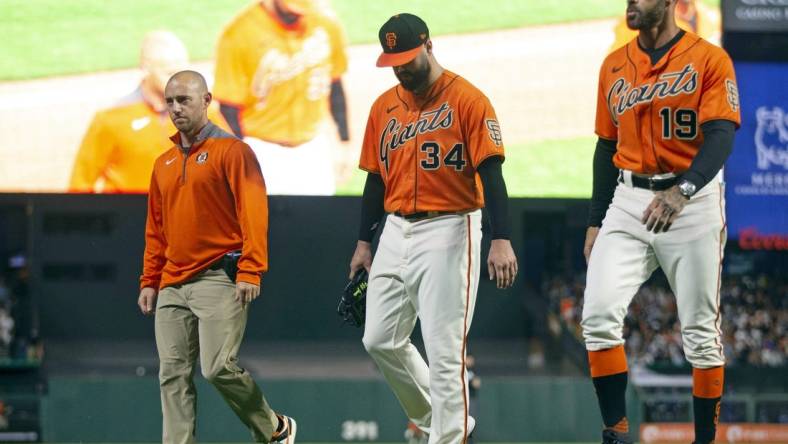 Jun 10, 2022; San Francisco, California, USA; San Francisco Giants starting pitcher Jakob Junis (34) leaves the field with an injury accompanied by manager Gabe Kapler (19) and assistant athletic trainer L.J. Petra during the sixth inning against the Los Angeles Dodgers at Oracle Park. Mandatory Credit: D. Ross Cameron-USA TODAY Sports