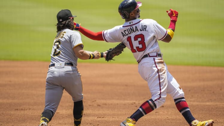 Jun 12, 2022; Cumberland, Georgia, USA; Atlanta Braves right fielder Ronald Acuna Jr. (13) gets back to first base ahead of the tag by Pittsburgh Pirates first baseman Michael Chavis (2) during the first inning at Truist Park. Mandatory Credit: Dale Zanine-USA TODAY Sports