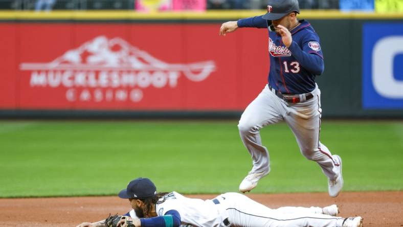 Jun 13, 2022; Seattle, Washington, USA; Minnesota Twins left fielder Trevor Larnach (13) jumps over Seattle Mariners shortstop J.P. Crawford (3) to advance to third base on a hit by a teammate during the second inning at T-Mobile Park. Mandatory Credit: Joe Nicholson-USA TODAY Sports