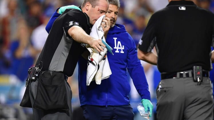 Jun 14, 2022; Los Angeles, California, USA; Home plate umpire Nate Tomlinson is helped by Los Angeles Dodgers trainer Nate Lucero after being hit by the bat of Los Angeles Angels center fielder Mike Trout (27) during the ninth inning at Dodger Stadium. Mandatory Credit: Gary A. Vasquez-USA TODAY Sports