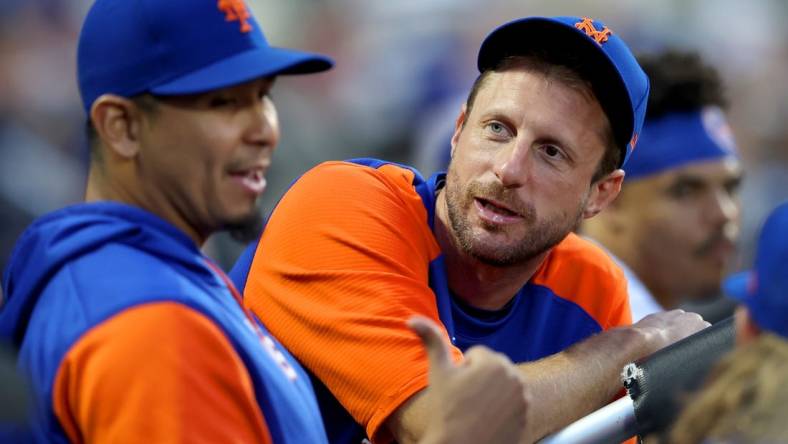 Jun 15, 2022; New York City, New York, USA; New York Mets injured pitcher Max Scherzer (21) talks to starting pitcher Carlos Carrasco (59) in the dugout during the third inning against the Milwaukee Brewers at Citi Field. Mandatory Credit: Brad Penner-USA TODAY Sports