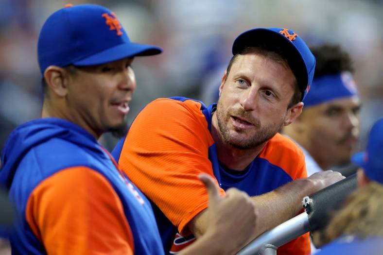 Jun 15, 2022; New York City, New York, USA; New York Mets injured pitcher Max Scherzer (21) talks to starting pitcher Carlos Carrasco (59) in the dugout during the third inning against the Milwaukee Brewers at Citi Field. Mandatory Credit: Brad Penner-USA TODAY Sports