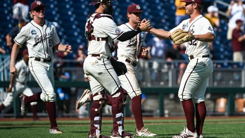 Jun 19, 2022; Omaha, NE, USA;  Texas A&M Aggies pitcher Brad Rudis (32) and catcher Troy Claunch (12) celebrate the win against the Texas Longhorns at Charles Schwab Field. Mandatory Credit: Steven Branscombe-USA TODAY Sports