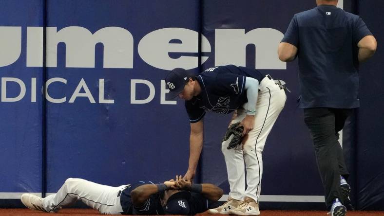 Jun 20, 2022; St. Petersburg, Florida, USA;  Injured Tampa Bay Rays right fielder Manuel Margot (13) is checked on by  Brett Phillips (35) as a trainer runs to assist at Tropicana Field. Mandatory Credit: Dave Nelson-USA TODAY Sports