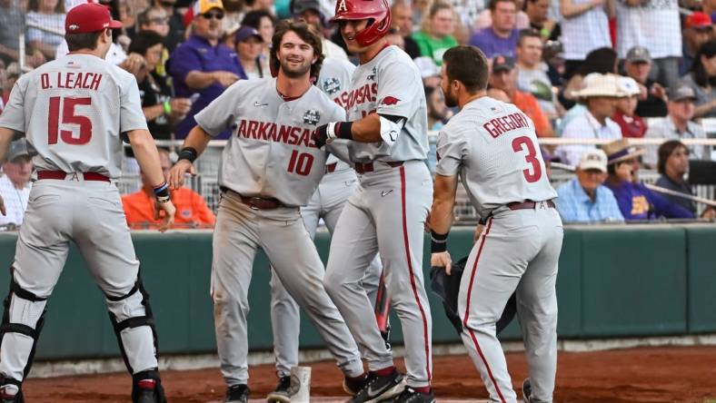 Jun 21, 2022; Omaha, NE, USA;  Arkansas Razorbacks right fielder Chris Lanzilli (18) greets catcher Dylan Leach (15) and first baseman Peyton Stovall (10)  and left fielder Zack Gregory (3) after hitting a home run against the Auburn Tigers in the fourth inning at Charles Schwab Field. Mandatory Credit: Steven Branscombe-USA TODAY Sports