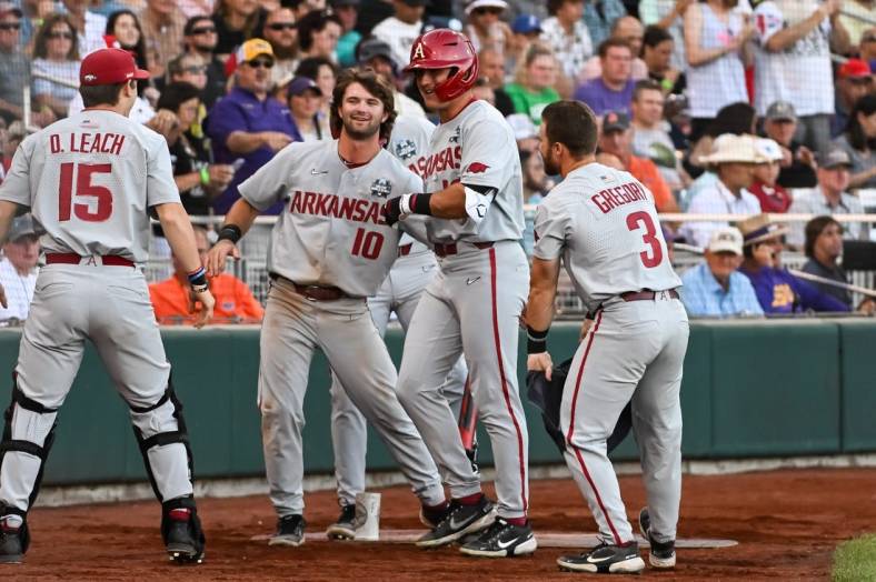 Jun 21, 2022; Omaha, NE, USA;  Arkansas Razorbacks right fielder Chris Lanzilli (18) greets catcher Dylan Leach (15) and first baseman Peyton Stovall (10)  and left fielder Zack Gregory (3) after hitting a home run against the Auburn Tigers in the fourth inning at Charles Schwab Field. Mandatory Credit: Steven Branscombe-USA TODAY Sports