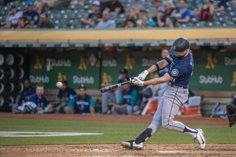 Jun 21, 2022; Oakland, California, USA; Seattle Mariners right fielder Jesse Winker (27) hits an rbi single during the fifth inning against the Oakland Athletics at RingCentral Coliseum. Mandatory Credit: Ed Szczepanski-USA TODAY Sports