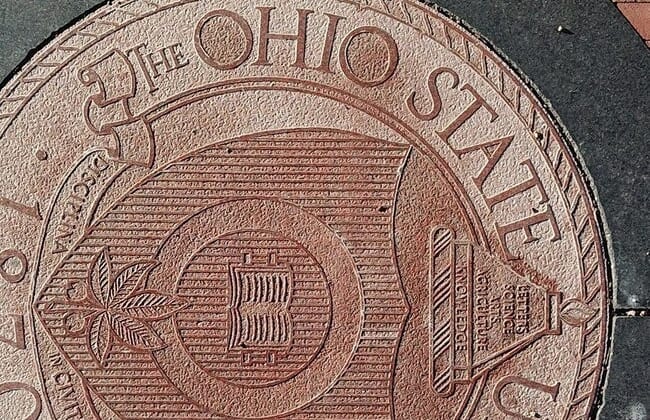 Ohio State University regularly uses the definitive article "The" in front of its name, as seen here in the university seal embedded in the pavement at the east entrance to the Oval on the main campus in Columbus.The Ohio State University