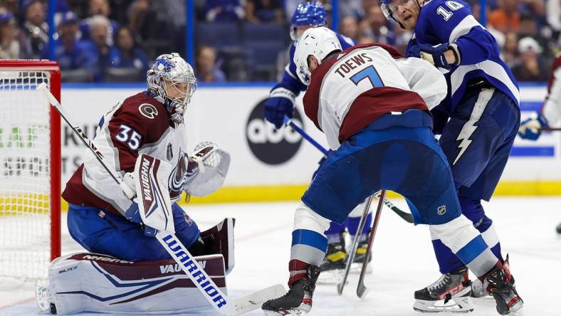 Jun 22, 2022; Tampa, Florida, USA; Tampa Bay Lightning right wing Corey Perry (10) and defenseman Devon Toews (7) battle for the puck in front of goaltender Darcy Kuemper (35) during the second period in game four of the 2022 Stanley Cup Final at Amalie Arena. Mandatory Credit: Geoff Burke-USA TODAY Sports