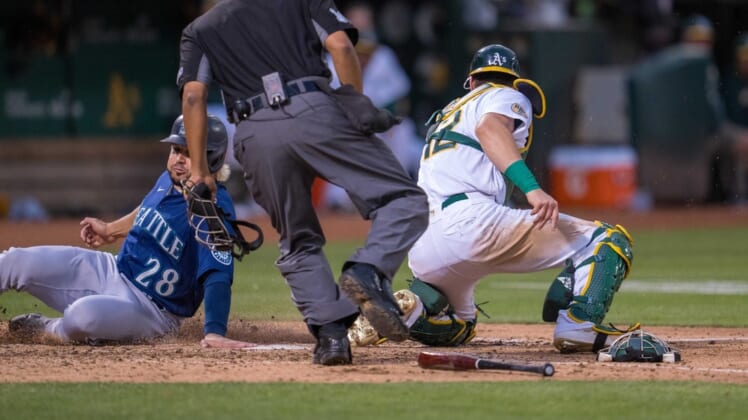 Jun 22, 2022; Oakland, California, USA; Seattle Mariners third baseman Eugenio Suarez (28) slides in safely at home plate during the fifth inning against Oakland Athletics catcher Sean Murphy (12) at RingCentral Coliseum. Mandatory Credit: Neville E. Guard-USA TODAY Sports
