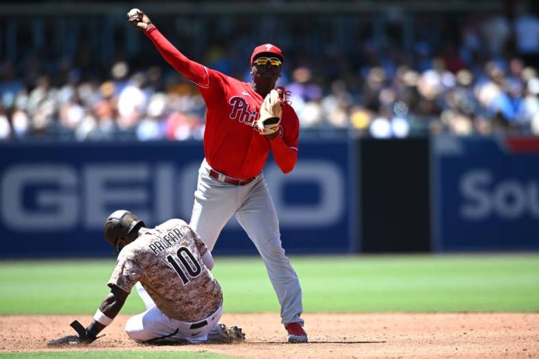 Jun 26, 2022; San Diego, California, USA; Philadelphia Phillies shortstop Didi Gregorius (top) throws to first base late after forcing out San Diego Padres left fielder Jurickson Profar (10) at second base during the third inning at Petco Park. Mandatory Credit: Orlando Ramirez-USA TODAY Sports