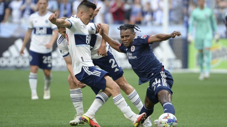 Jun 26, 2022; Vancouver, British Columbia, CAN;  New England Revolution forward DeJuan Jones (24) reaches for the ball against Vancouver Whitecaps defender Marcus Godinho (2) during the first half at BC Place. Mandatory Credit: Anne-Marie Sorvin-USA TODAY Sports