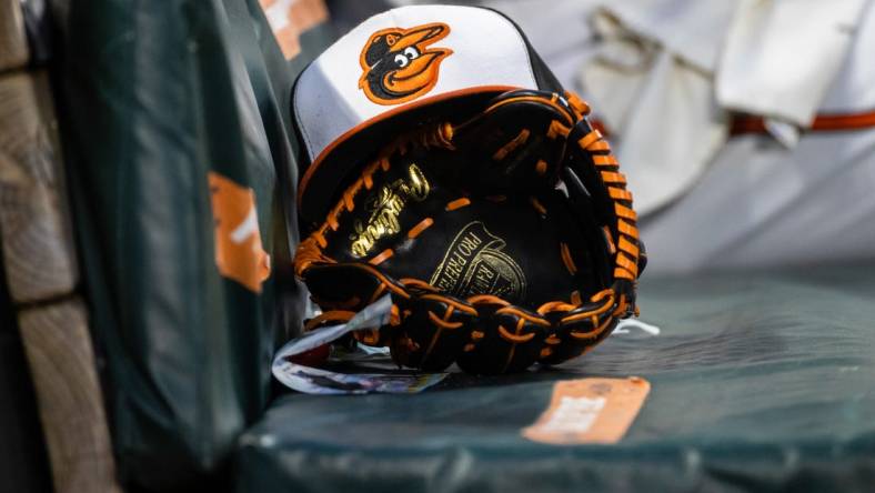 Jun 1, 2021; Baltimore, Maryland, USA; A Baltimore Orioles hat and glove are seen in the dugout during the fourth inning of the game between the Baltimore Orioles and the Minnesota Twins at Oriole Park at Camden Yards. Mandatory Credit: Scott Taetsch-USA TODAY Sports