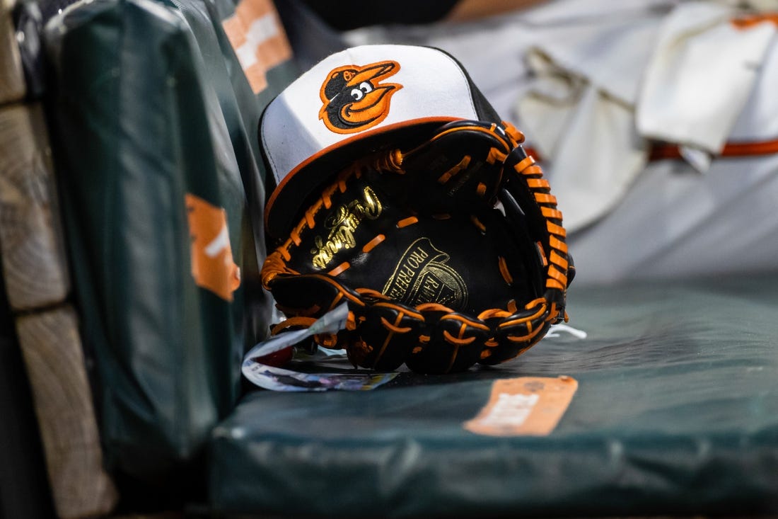 Jun 1, 2021; Baltimore, Maryland, USA; A Baltimore Orioles hat and glove are seen in the dugout during the fourth inning of the game between the Baltimore Orioles and the Minnesota Twins at Oriole Park at Camden Yards. Mandatory Credit: Scott Taetsch-USA TODAY Sports