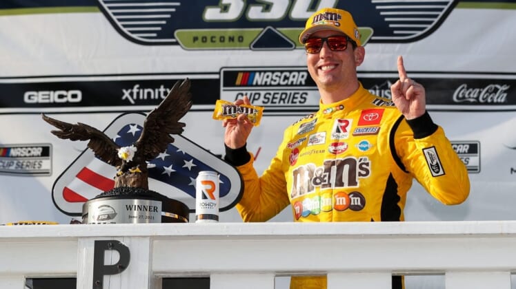 Jun 27, 2021; Long Pond, Pennsylvania, USA; NASCAR Cup Series driver Kyle Busch (18) celebrates in victory lane after winning the Explore the Pocono Mountains 350 at Pocono Raceway. Mandatory Credit: Matthew OHaren-USA TODAY Sports