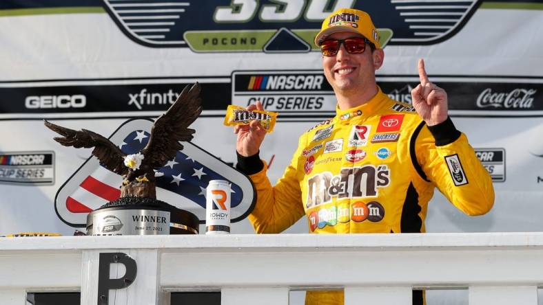 Jun 27, 2021; Long Pond, Pennsylvania, USA; NASCAR Cup Series driver Kyle Busch (18) celebrates in victory lane after winning the Explore the Pocono Mountains 350 at Pocono Raceway. Mandatory Credit: Matthew OHaren-USA TODAY Sports