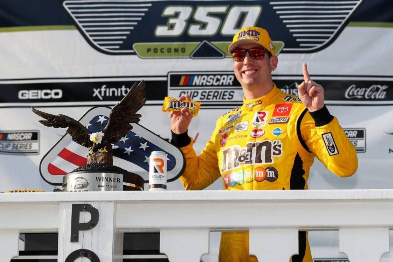 Jun 27, 2021; Long Pond, Pennsylvania, USA; NASCAR Cup Series driver Kyle Busch (18) celebrates in victory lane after winning the Explore the Pocono Mountains 350 at Pocono Raceway. Mandatory Credit: Matthew OHaren-USA TODAY Sports