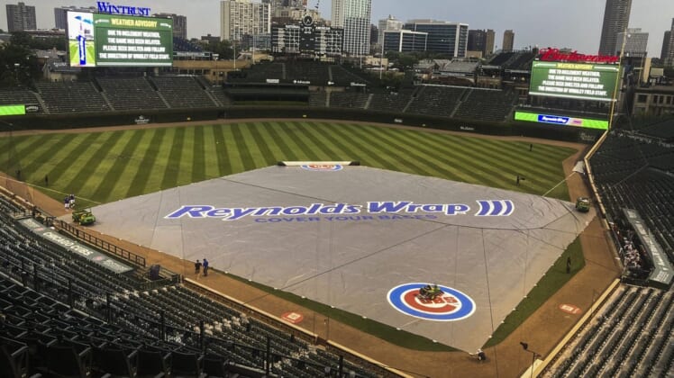 Jul 24, 2021; Chicago, Illinois, USA; Chicago Cubs grounds crew members place the tarp during a rain delay in the ninth inning against the Arizona Diamondbacks at Wrigley Field. Mandatory Credit: Matt Marton-USA TODAY Sports