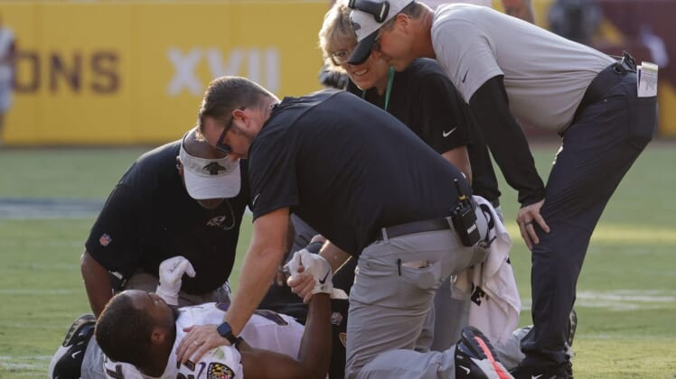 Aug 28, 2021; Landover, Maryland, USA; Baltimore Ravens head coach John Harbaugh (R) looks on as team medical personnel help Ravens running back J.K. Dobbins (27) after being injured against the Washington Football Team in the first quarter at FedExField. Mandatory Credit: Geoff Burke-USA TODAY Sports