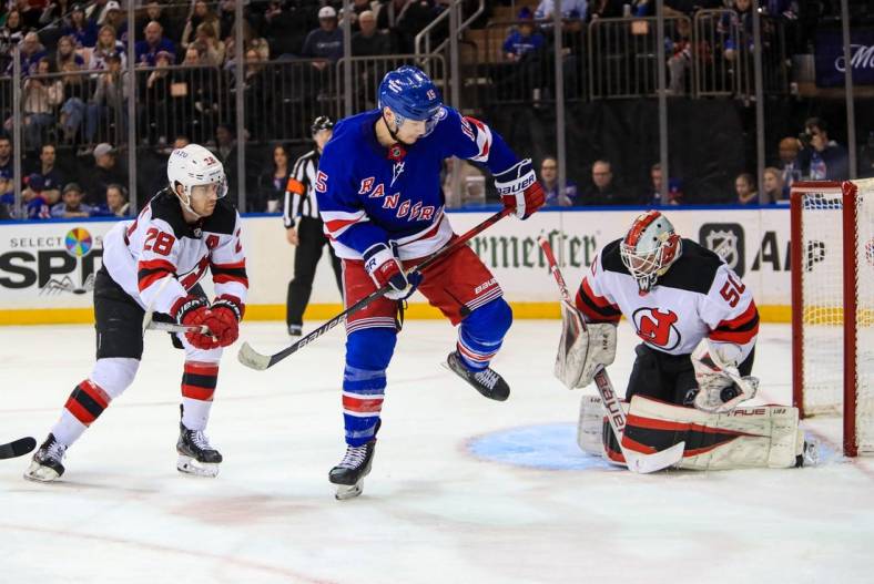 Mar 4, 2022; New York, New York, USA; New York Rangers right wing Julien Gauthier (15) tries to deflect a puck past New Jersey Devils goalie Nico Daws (50) as defenseman Damon Severson (28) defends during the second period at Madison Square Garden. Mandatory Credit: Danny Wild-USA TODAY Sports