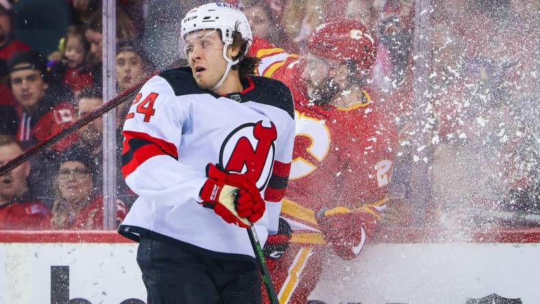 Mar 16, 2022; Calgary, Alberta, CAN; New Jersey Devils defenseman Ty Smith (24) and Calgary Flames center Dillon Dube (29) battle for the puck during the first period at Scotiabank Saddledome. Mandatory Credit: Sergei Belski-USA TODAY Sports