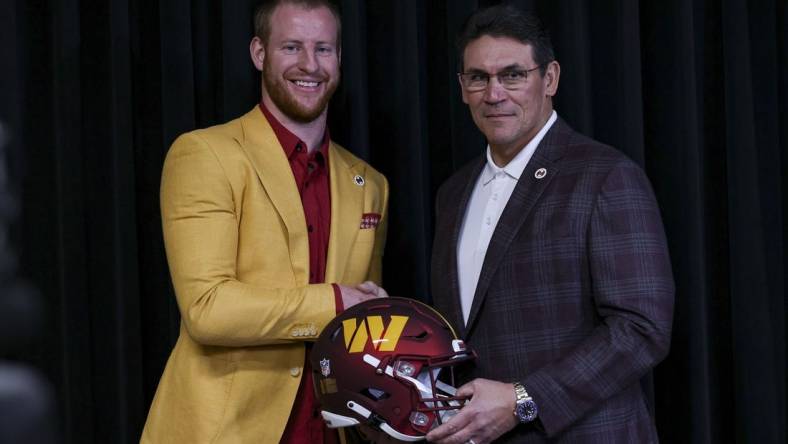 Mar 17, 2022; Ashburn, VA, USA;  Washington Commanders quarterback Carson Wentz and head coach Ron Rivera pose with the team helmet at Inova Sports Performance Center Auditorium. Mandatory Credit: John McCreary-USA TODAY Sports