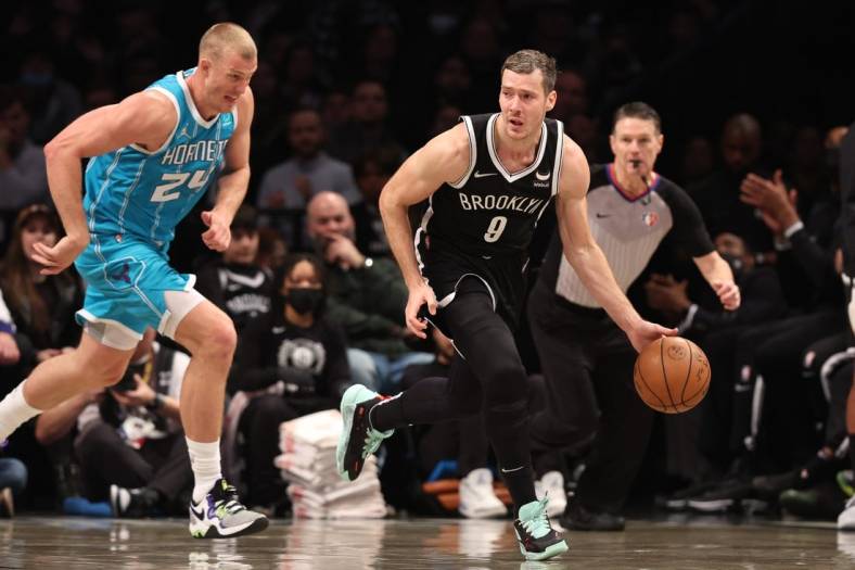 Mar 27, 2022; Brooklyn, New York, USA; Brooklyn Nets guard Goran Dragic (9) dribbles up court in front of Charlotte Hornets center Mason Plumlee (24) during the second half at Barclays Center. Mandatory Credit: Vincent Carchietta-USA TODAY Sports