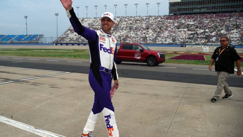 Jun 26, 2022; Nashville, Tennessee, USA; NASCAR Cup Series driver Denny Hamlin (11) waves to fans as he makes his way back to his car following a weather delay during the Ally 400 at Nashville Superspeedway. Mandatory Credit: Christopher Hanewinckel-USA TODAY Sports