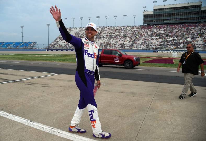 Jun 26, 2022; Nashville, Tennessee, USA; NASCAR Cup Series driver Denny Hamlin (11) waves to fans as he makes his way back to his car following a weather delay during the Ally 400 at Nashville Superspeedway. Mandatory Credit: Christopher Hanewinckel-USA TODAY Sports
