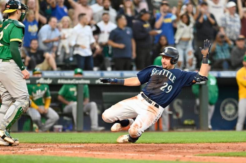 Jun 30, 2022; Seattle, Washington, USA; Seattle Mariners catcher Cal Raleigh (29) scores a run on an error after hitting a two-RBI triple against the Oakland Athletics during the fifth inning at T-Mobile Park. Mandatory Credit: Steven Bisig-USA TODAY Sports