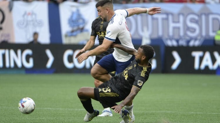 Jul 2, 2022; Vancouver, British Columbia, CAN;  Los Angeles FC midfielder Kellyn Acosta (23) collides with Vancouver Whitecaps forward Lucas Cavallini (9) during the first half at BC Place. Mandatory Credit: Anne-Marie Sorvin-USA TODAY Sports