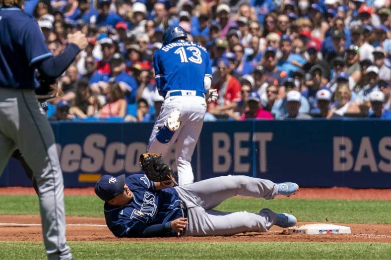 Jul 3, 2022; Toronto, Ontario, CAN; Tampa Bay Rays first baseman Ji-Man Choi (26) tags out Toronto Blue Jays left fielder Lourdes Gurriel Jr. (13) at first base during the second inning at Rogers Centre. Mandatory Credit: Kevin Sousa-USA TODAY Sports