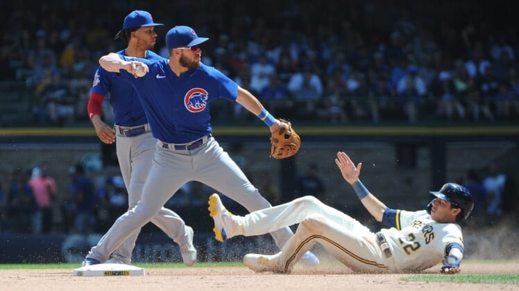 Jul 6, 2022; Milwaukee, Wisconsin, USA; Milwaukee Brewers left fielder Christian Yelich (22) attempts to break up the double play throw of Chicago Cubs third baseman Patrick Wisdom (16) in the fourth inning at American Family Field. Mandatory Credit: Michael McLoone-USA TODAY Sports