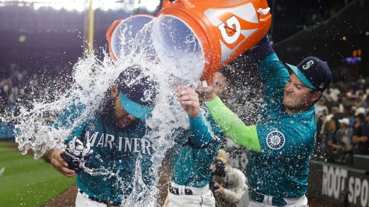 Jul 8, 2022; Seattle, Washington, USA; Seattle Mariners third baseman Eugenio Suarez (28) is doused with water by designated hitter Ty France (23, right) after hitting a walk-off home run against the Toronto Blue Jays during the eleventh inning at T-Mobile Park. Mandatory Credit: Joe Nicholson-USA TODAY Sports