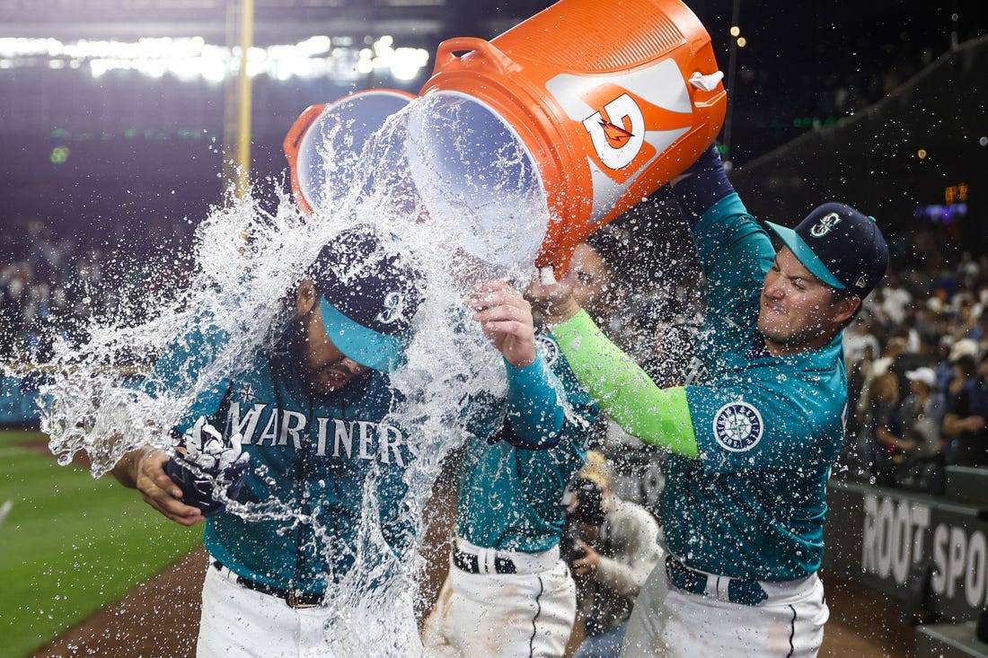 Jul 8, 2022; Seattle, Washington, USA; Seattle Mariners third baseman Eugenio Suarez (28) is doused with water by designated hitter Ty France (23, right) after hitting a walk-off home run against the Toronto Blue Jays during the eleventh inning at T-Mobile Park. Mandatory Credit: Joe Nicholson-USA TODAY Sports