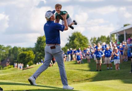 Jul 10, 2022; Nicholasville, Kentucky, USA; Trey Mullinax lifts up his two-year-old son Jude on the 18th green during the final round of the Barbasol Championship golf tournament. Mandatory Credit: Jordan Prather-USA TODAY Sports