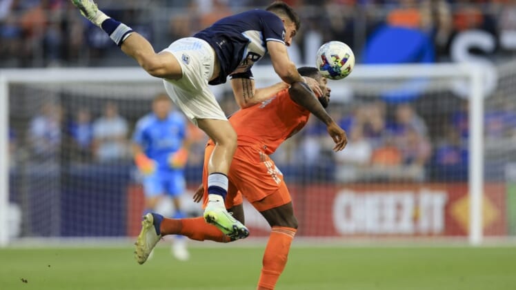 Jul 13, 2022; Cincinnati, Ohio, USA; Vancouver Whitecaps forward Lucas Cavallini (top) attempts to play the ball against FC Cincinnati defender Tyler Blackett (24) in the first half at TQL Stadium. Mandatory Credit: Aaron Doster-USA TODAY Sports
