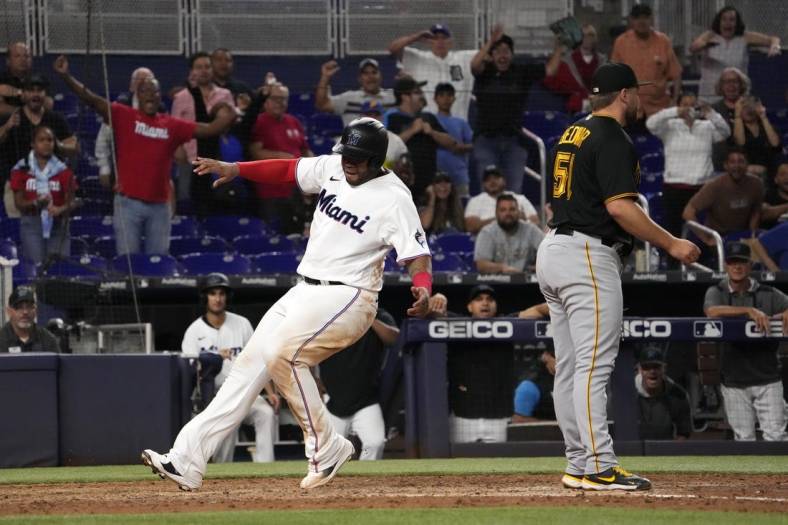 Jul 13, 2022; Miami, Florida, USA; Miami Marlins first baseman Jesus Aguilar (99) scores the game winning run on a wild pitch by Pittsburgh Pirates relief pitcher David Bednar (51) in the tenth inning at loanDepot park. Mandatory Credit: Jasen Vinlove-USA TODAY Sports