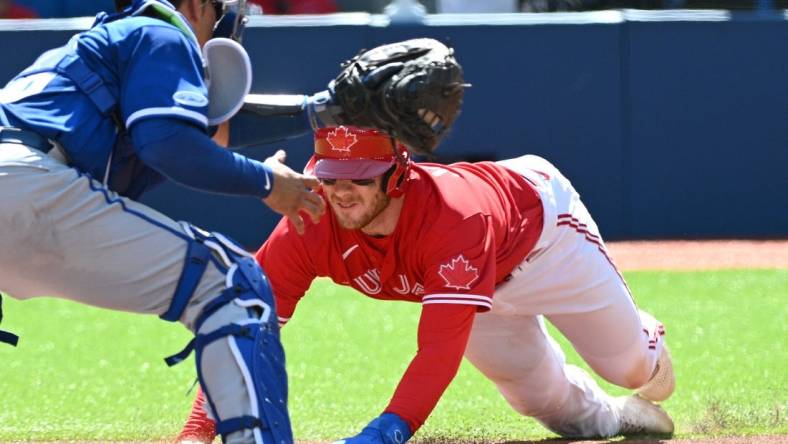 Jul 16, 2022; Toronto, Ontario, CAN;  Toronto Blue Jays catcher Danny Jansen (9) slides to score past Kansas City Royals catcher Freddy Fermin (78) in the third inning at Rogers Centre. Mandatory Credit: Dan Hamilton-USA TODAY Sports