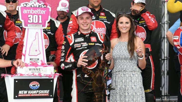Jul 17, 2022; Loudon, New Hampshire, USA; NASCAR Cup Series driver Christopher Bell (20) and wife Morgan Kemenah celebrate on victory lane with Loudon the lobster after the Ambetter 301 at New Hampshire Motor Speedway. Mandatory Credit: Eric Canha-USA TODAY Sports