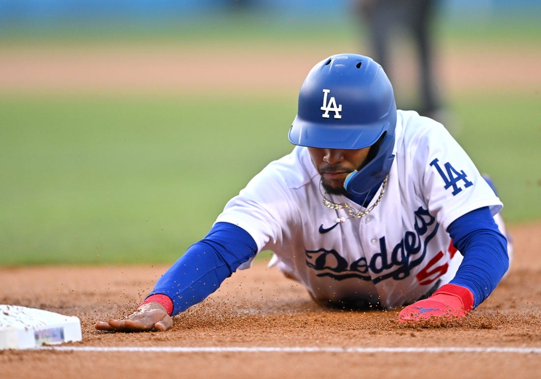 Los Angeles Dodgers' Mookie Betts, left, dives back to first on a
