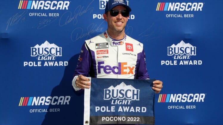 Jul 23, 2022; Long Pond, Pennsylvania, USA; NASCAR Cup Series driver Denny Hamlin poses with the pole award after winning the pole during practice and qualifying for the M&Ms Fan Appreciation 400 at Pocono Raceway. Mandatory Credit: Matthew OHaren-USA TODAY Sports