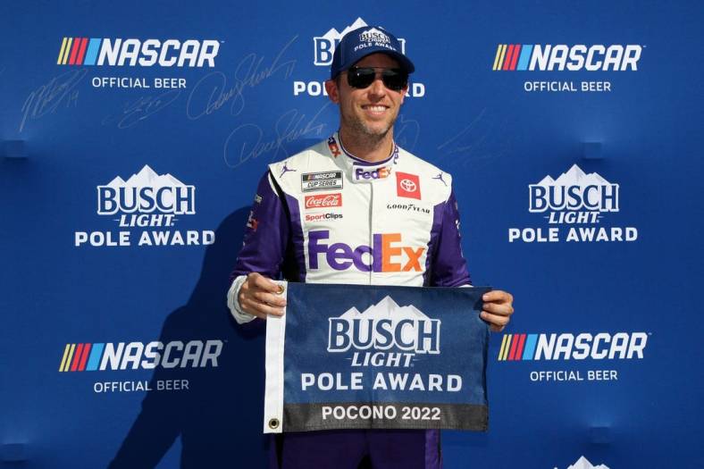 Jul 23, 2022; Long Pond, Pennsylvania, USA; NASCAR Cup Series driver Denny Hamlin poses with the pole award after winning the pole during practice and qualifying for the M&Ms Fan Appreciation 400 at Pocono Raceway. Mandatory Credit: Matthew OHaren-USA TODAY Sports