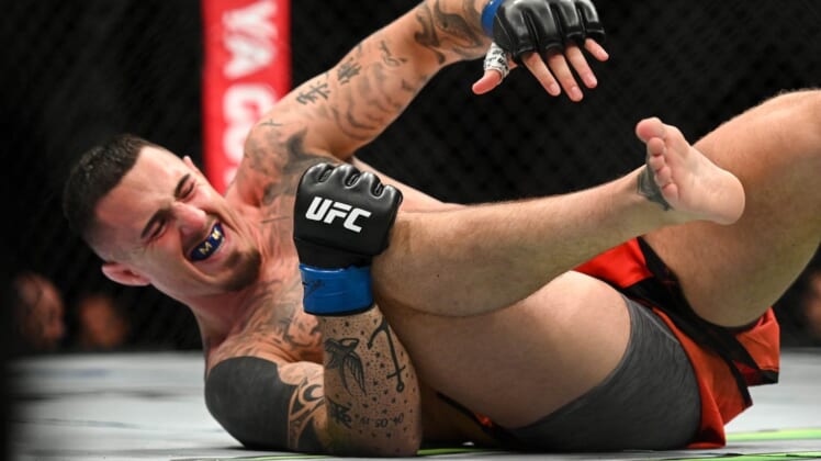 Jul 23, 2022; London, United Kingdom;  Tom Aspinall (blue gloves) falls to the ground while fighting Curtis Blaydes during UFC Fight Night at O2 Arena. Mandatory Credit: Per Haljestam-USA TODAY Sports
