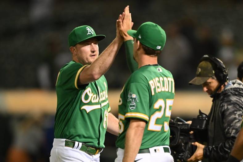 Jul 23, 2022; Oakland, California, USA; Oakland Athletics relief pitcher Zach Jackson (61) and right fielder Stephen Piscotty (25) shake hands after the final out of the ninth inning against the Texas Rangers at RingCentral Coliseum. Mandatory Credit: Robert Edwards-USA TODAY Sports