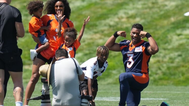 Jul 27, 2022; Englewood, CO, USA; Denver Broncos quarterback Russell Wilson (3) and wife his Ciara Wilson pose for photos with their children following training camp at the UCHealth Training Center. Mandatory Credit: Ron Chenoy-USA TODAY Sports