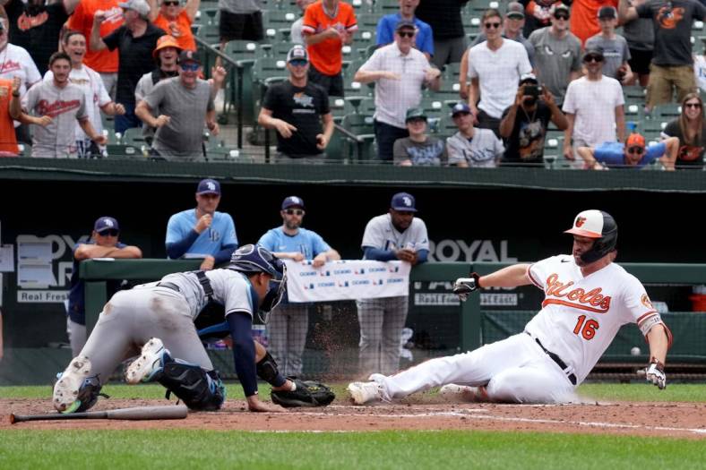 Jul 28, 2022; Baltimore, Maryland, USA; Baltimore Orioles designated hitter Trey Mancini (16) slides in safely for a two-run, inside-the-park home run in the eighth inning against Tampa Bay Rays catcher Rene Pinto (50) at Oriole Park at Camden Yards. Mandatory Credit: Mitch Stringer-USA TODAY Sports