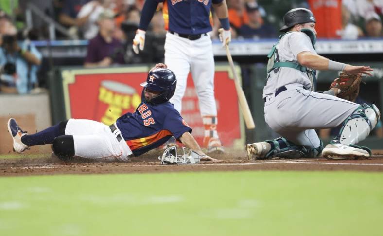 Jul 31, 2022; Houston, Texas, USA;  Houston Astros second baseman Jose Altuve (27) steals home plate as Seattle Mariners catcher Cal Raleigh (29) awaits the throw in the first inning at Minute Maid Park. Mandatory Credit: Thomas Shea-USA TODAY Sports